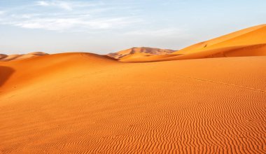 Mavi gökyüzü olan çöl manzaraları. Yuvarlak şekilli kum tepecikleri. Doğal değişimlerin güzelliği.