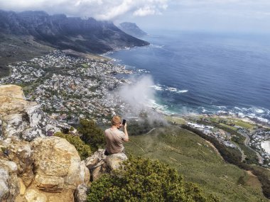 Bir turist, Güney Afrika 'daki Lions Head Dağı' ndan Cape Town (Kamp Koyu) ve Güney Atlantik Okyanusu manzarasına hayran.