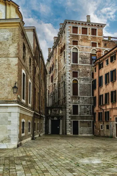 Facades of weathered buildings with windows on street of Venice city, Italy