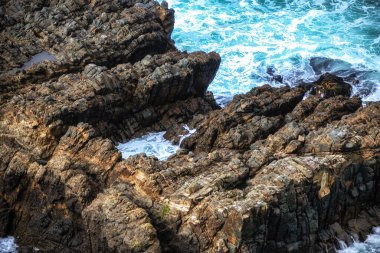 Caitlans, Yeni Zelanda 'daki Nugget Point' te okyanusu delen kayaları kapatın.
