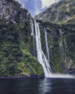 Milford Sound, NZ 'de bulut yakalayan dağdan güzel şelale.