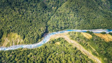 Yeşil açıklık havası, orman ve Wilkin nehrindeki çakıl taşlı nehir yatağı, yukarıdan çekilen parlak bahar ışığı, Otago, Güney Adası, Yeni Zelanda