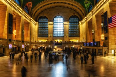 New York, ABD - 22 Aralık 2023: New York 'taki Grand Central Terminali' nde insanların yürüdüğü ve Amerikan bayrağının belirgin bir şekilde sergilendiği hareketli bir sahne.