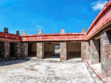 Teotihuacan, Meksika 'da bulunan antik bir sarayın karmaşık avlusunda oyulmuş taş sütunlar ve açık mavi ve kırmızı boyanmış detaylar sergileniyor.