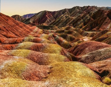 Amazing scenery of Rainbow mountain and blue sky background in sunset. Zhangye Danxia National Geopark, Gansu, China. Colorful landscape, rainbow hills, unusual colored rocks, sandstone erosion clipart