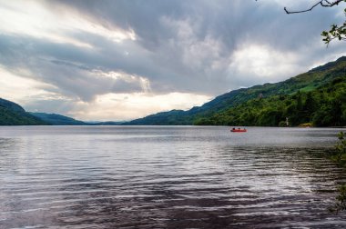 İskoçya dağlarında Lomond Gölü 'nün sakin yüzeyi bir göl teknesiyle.