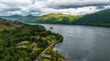 Güzel Lomond Gölü, İskoçya, İngiltere 'de bir yaz günü nefes kesen bir manzarada su ve dağları gösteriyor. Popüler bir turizm merkezi..