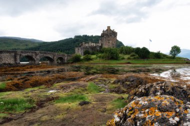 Eilean Donan Şatosu, sonbahar renklerinin ortasında heybetli bir şekilde duruyor, yansıması sakin sularda parıldıyor. Misty Highlands ve altın ağaçlar sonsuz bir güzellik manzarası yaratır..