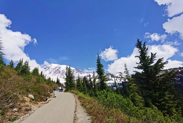 Τουρίστες Που Περπατούν Ασφαλτοστρωμένο Δρόμο Όμορφο Τοπίο Βουνά Και Γαλάζιο — Φωτογραφία Αρχείου