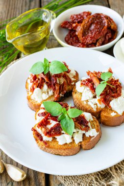 Tahtada kurutulmuş domatesli, peynirli, sarımsaklı ve fesleğenli beyaz ekmek sandviçleri.