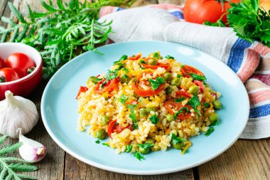 Tahta arka planda beyaz seramik tabakta sebzeli bulgur güveci.