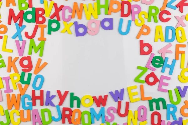 Colorful alphabet magnets on whiteboard making frame for copy space