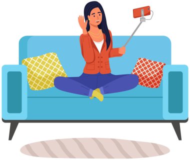 Kız selfie çekiyor. Akıllı telefonlu mutlu bir kadın evde oturmuş fotoğraf çekiyor ve konuşuyor. Video aracılığıyla iletişim kuruyor. Moda özçekimi, resim için poz, fotoğraf modern aygıt.