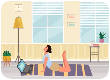 Evde egzersiz yapan genç bir kadın var. Kız minderde yoga yapıyor. Sporcu kadın dairede esniyor. Yogi bilgisayarda video ile fiziksel egzersiz yapar. Sağlıklı yaşam tarzı ve spor aktiviteleri