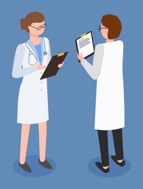 Doktor ve hemşire hastanede tıbbi muayeneyi tartışıyorlar. Beyaz önlük giymiş iki kadın doktor, hasta test verilerini tartışıyor, reçeteli ilaçları kişisel kartta kontrol ediyorlar.