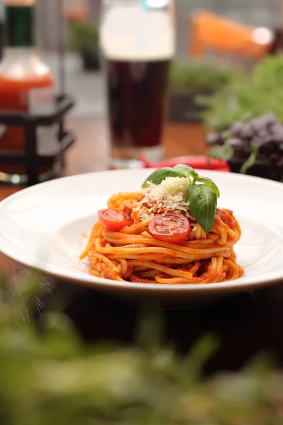 Tomato spaghetti with basil and cheese on a white plate in a restaurant, with blurred background, Italian pasta, with cherry tomatoes, Italian dinner,red sauce, Mediterranean cuisine, bolognese
