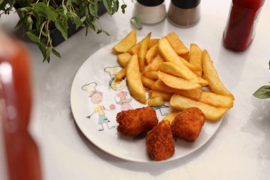 Beyaz tabakta patates kızartması olan külçelerin üst görüntüsü, seçici odaklanma. Öğle yemeği, çocuk porsiyonu. Küçük ekmeklenmiş tavuk, et parçaları, ev yapımı cips, yakın plan, bulanık arka plan..