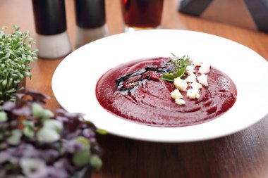 Beyaz kasede pancar çorbası. Kırmızı krema çorbası, peynirle süslenmiş, roka ve balzamik sirke, bulanık arkaplan.. 