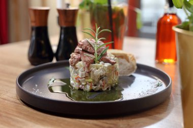 Yoğurt soslu sebze salatası. Kızarmış et, biftek ve çıtır ciabatta ile servis ediliyor. Zarif, siyah bir tabakta. Restoranda öğle yemeği..