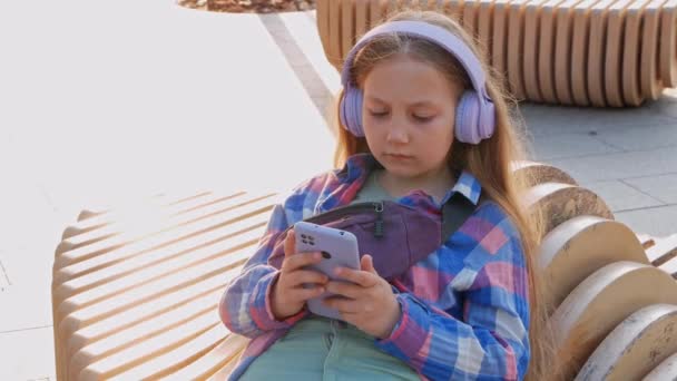Blondynka Dzieci Słuchawki Kratkę Koszula Słuchać Muzyki Podcast Smartfon Poza — Wideo stockowe