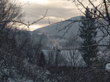 Evlerin bacasından duman çıkıyor. Transcarpathia bölgesindeki bir köyde kış mevsimi. Karlı Karpatya dağları Ukrayna, Avrupa 'ya bakıyor. Sonbahar kırsal arazisi.