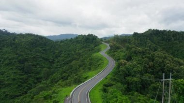 Yağmur mevsiminde, Nan, Tayland 'daki tropikal yağmur ormanları dağında, dolambaçlı yolun üzerinde uçan hava aracı. Broll görüntüleri, dolambaçlı ve tehlikeli yolların hava görüntüleri.