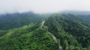 Yağmur mevsiminde, Nan, Tayland 'daki tropikal yağmur ormanları dağında, dolambaçlı yolun üzerinde uçan hava aracı. Broll görüntüleri, dolambaçlı ve tehlikeli yolların hava görüntüleri.