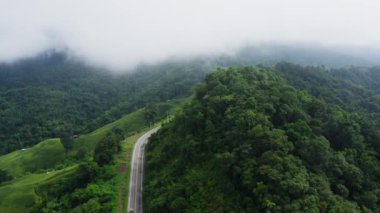 Yağmur mevsiminde, Nan, Tayland 'daki tropikal yağmur ormanları dağında, dolambaçlı yolun üzerinde uçan hava aracı. Broll görüntüleri, dolambaçlı ve tehlikeli yolların hava görüntüleri.