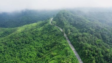 Yağmur mevsiminde, Nan, Tayland 'daki tropikal yağmur ormanları dağında, dolambaçlı yolun üzerinde uçan hava aracı. Broll görüntüleri, dolambaçlı ve tehlikeli yolların hava görüntüleri.
