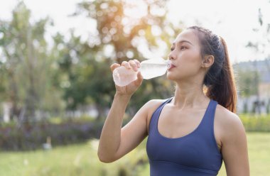 Şişeden temiz su içen kadın. Kadınlar koşudan sonra su içer. Egzersiz ve spor sonrası kadın içme suyu. Sporcu kadın antrenmandan sonra dinlenip su içiyor..
