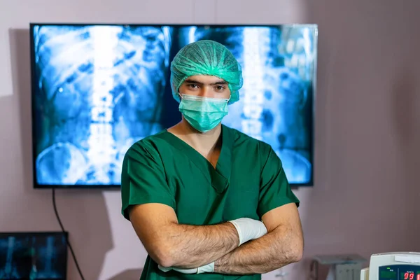 Man wearing green surgical gown standing with arms crossed in operating room, show readiness start surgery for patients who waiting for treatment. Virtual surgery simulation