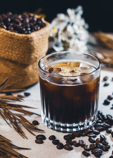 杯子里的冰咖啡 咖啡豆里的黑咖啡 夏日冷饮在木制桌子上 有复制空间 冰镇美式咖啡 — 图库照片#
