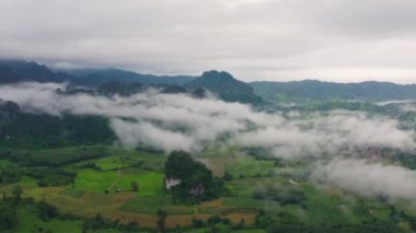 Beyaz bulutların üzerinde uçan hava aracı yoğun sis bulutu hızla hareket ediyor. İHA yağmurlu gökyüzünde kabarık bulutların arasından geri uçuyor. Güzel sisli ve bulutlu yavaş hareket eden hava manzarası. Sis denizi. Phu Lang Ka