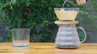 Fransız kahvesi demleniyor. Çaydanlıktan gelen sıcak suyu kahve zeminine dökerek tahtadan yeşil ağaç zeminli kahve çıkararak. Rahatlamaya kahve zamanı. Tatilde. Yavaş çekim 4k B-rulo.