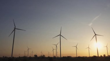 Rüzgar türbinlerinin enerji tasarrufu teknolojisi dünyayı kurtarmak için bir çözümdür. Gün batımında gökyüzünde çekilmiş. Güzel günbatımı gökyüzüne sahip rüzgar türbinleri. Küresel ısınma kavramı ve yeşil enerji. İklim değişikliği. Kamera B Kaydı