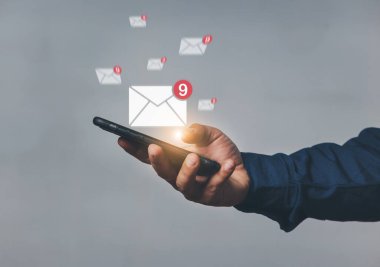 Ekranda e- posta simgesi olan el ele tutuşan cep telefonu. İş iletişim teknolojisi konsepti. Bir insan eli internetten e-posta gönderirken ve alırken telefonu tutar.