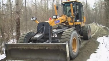 Kademe ve kamyon yolda bir duvar örüyor.