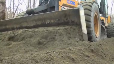 Kademe ve kamyon yolda bir duvar örüyor.