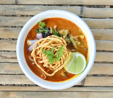 Khao Soi, Khao Soi Kai, Thai Noodles Khao Soi, ahşap zeminde baharatlı körili tavuk, Kuzey Tayland yemeği Lanna yemeği..