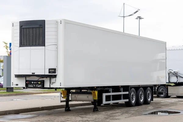 A new white refrigerated semi-trailer in the parking lot, waiting to be loaded with cargo. Freight commercial transport.