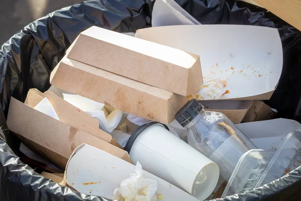 Recyclable waste in a container. Cardboard boxes, paper, bottles and plastic containers in an outdoor container for collecting recyclable waste. Caring for the environment.
