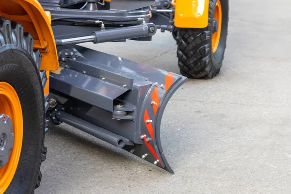 Close-up of the rotary blade of the new wheel grader. Sale of new construction and municipal equipment at a dealership or fair.