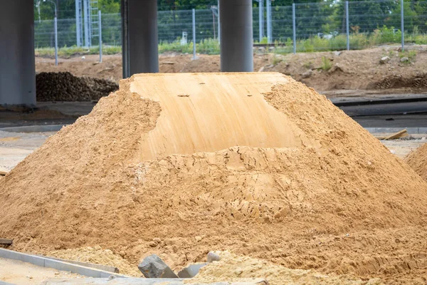 Pile of sand for road works. Construction or repair of a highway. A pile of clean bulk building material on a construction site. Creation of an urban environment.