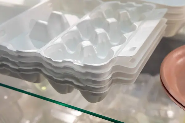 Stacks of white foam trays for packing eggs. Polystyrene foam trays are neatly stacked on top of each other. Packaging of products and goods.