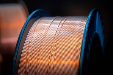Close-up of a spool of copper wire. Shiny copper wire wound on a reel, dark background, close-up. Electronics and industrial equipment. clipart