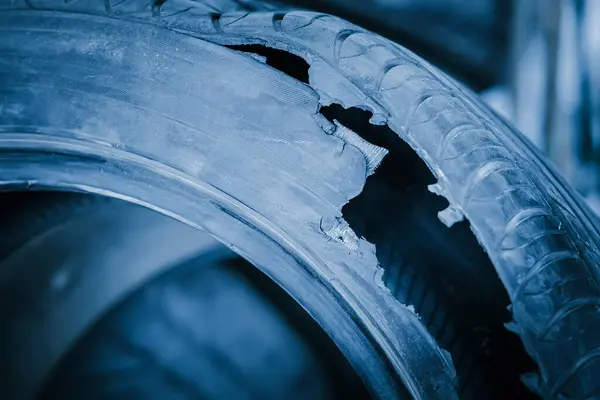 Torn tire. The result of a tire explosion close-up. Used tires for recycling using pyrolysis. Garbage or landfill or recycling. Change in repair service. Blue toning.