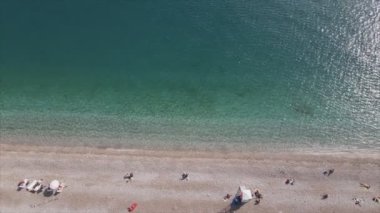 Bu video Türkiye 'de Akdeniz kıyısındaki bir plajın 8K çözünürlükteki havadan görüntüsünü gösteriyor