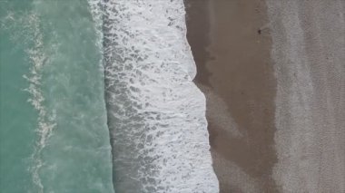 Bu video Türkiye 'de Akdeniz kıyısındaki bir plajın 8K çözünürlükteki havadan görüntüsünü gösteriyor