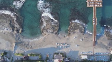 Bu video Türkiye 'de Akdeniz kıyısındaki bir plajın 8K çözünürlükteki havadan görüntüsünü gösteriyor