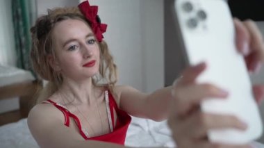 This stock video shows a young girl taking a selfie on her phone, slow motion